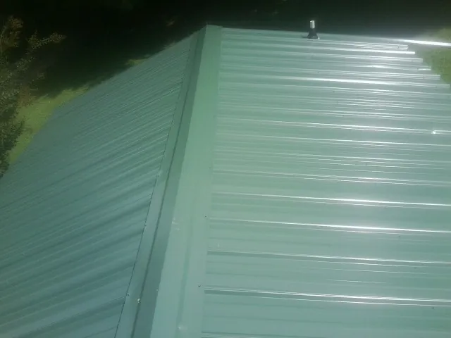 New green metal panels meeting at the ridge of a roof — Flat Roof Repair work by our crew in Nocatee